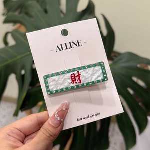 Dettaglio del fermaglio per capelli in acrilico verde con carattere rosso e strass