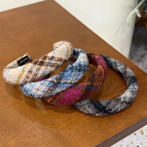 Detailed set of four tweed plaid headbands in various colors on a dark wooden surface