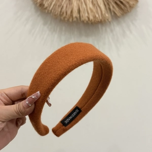 Detail of handmade orange brown wool headband with visible soft texture and label