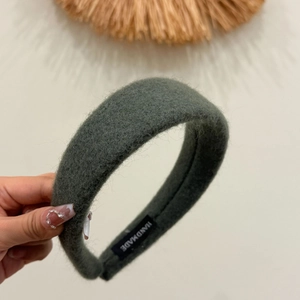 Detail of dark grey-green wool headband showing handmade label and plush fabric texture