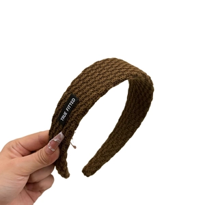 Schickes braunes Strickstirnband mit modischem schwarzem Markenetikett auf weißem Grund