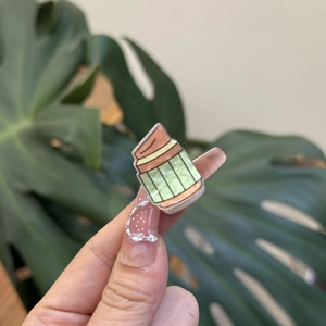 Close-up of a cute mini acrylic pencil jar hair clip with glitter finish and green hues