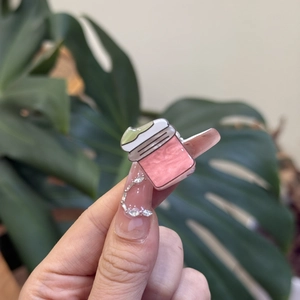 Close-up of pink mini jar nail charms with pearlescent finish on manicured nails