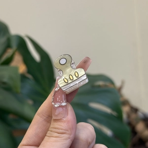 Detailed view of a mini cream yellow binder clip hair claw being held by hand