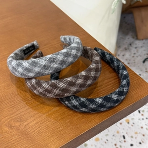 Detailed view of three padded wool headbands with plaid patterns in grey, brown and black