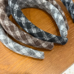Detail of wool plaid headbands in brown and grey tones on a natural wooden surface