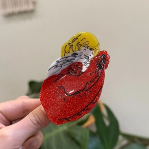 Détail de la pince à cheveux ange de dessin animé en acrylique rouge pailleté