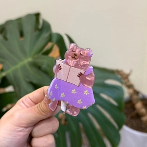 Detailed view of pink acrylic bear hair claw with floral dress and smooth texture