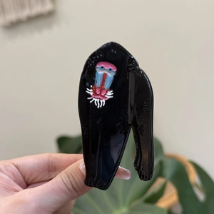 Detailed view of handmade acetate mandrill hair claw clip with colorful facial painting