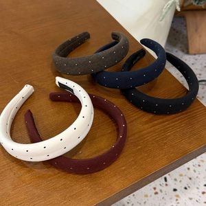 Detail view of five padded polka dot headbands in assorted colors on a wooden surface