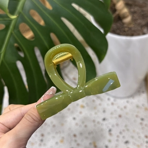 Elegant avocado green bow hair claw clip made of glossy resin with metal spring