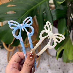 Dettaglio di forcine per capelli a farfalla in acetato blu marmo e bianco avorio