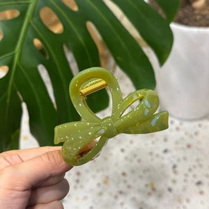 Elegant avocado green pumpkin bow hair claw clip held in hand for size demonstration