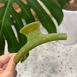 Detailed macro view of the elegant emerald green acrylic hair claw clip held by hand
