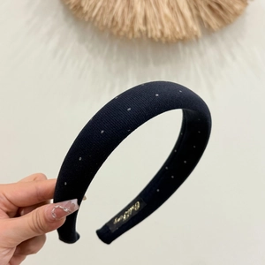 Close-up of black padded headband with silver polka dots and gold embroidered label