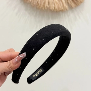Close-up of black velvet padded headband with silver glitter dots and golden label detail
