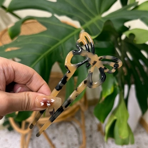 Dettaglio di un fermaglio per capelli a farfalla in acetato ambrato su foglia verde