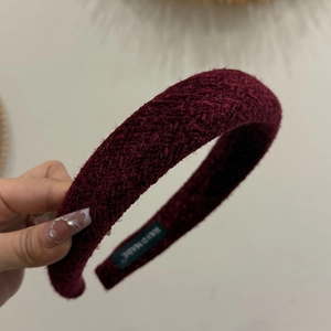 Detail of burgundy thick tweed headband featuring white HAND MADE woven label inside