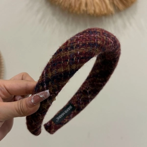 Detail view of wine red tweed padded headband with hand-made label and woven texture