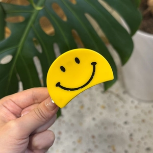 Pince à cheveux jaune en acétate avec visage souriant pour un style de coiffure ludique