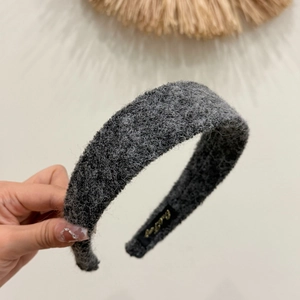 Close-up of deep gray felt headband showing soft wool texture and golden woven label