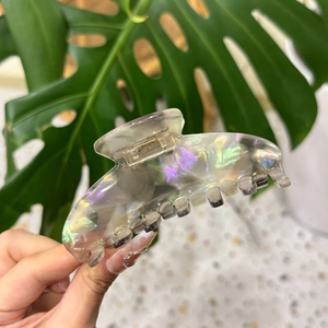 Détail d'une pince à cheveux en acétate holographique aux reflets violets et dorés