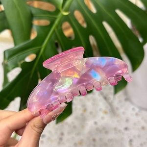Détail d'une grande pince à cheveux rose irisée avec motifs floraux et reflets nacrés