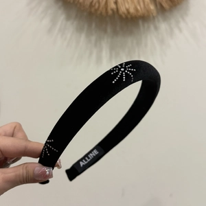 Detail of a black velvet headband with sparkling rhinestone star patterns and brand label