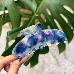 Grosse pince à cheveux en acétate avec texture marbrée irisée bleu et violet en gros plan