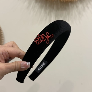 Close-up of velvet headband with red Chinese knot embroidery and branded inner label