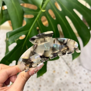 Détail d'une grande pince à cheveux en acétate avec texture marbrée nacrée et paillettes