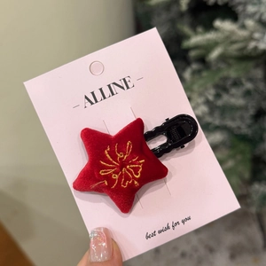 Festive red velvet star hair clip with gold embroidery on a pink card background