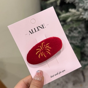 Macro shot of red velvet hair clip with gold firework embroidery on festive card