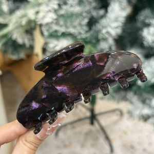 Détail macro d'une grande pince à cheveux en acétate avec paillettes violettes et roses
