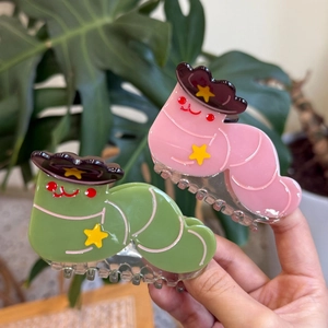 Détail de la pince à cheveux chat en acétate rose avec chapeau de cowboy tenue à la main