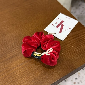 Détail d'un chouchou en velours rouge avec étiquette de marque sur surface en bois
