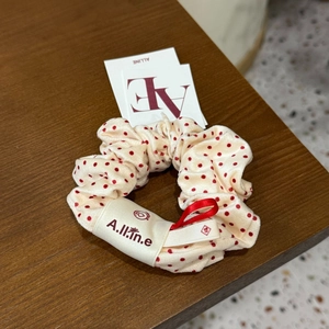 Détail d'un chouchou beige à pois rouges avec ruban satiné et étiquette de marque