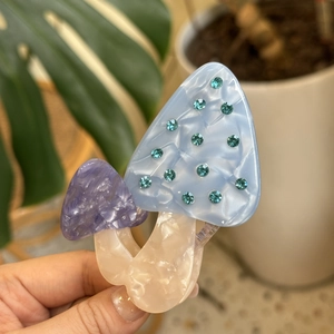Close-up of a blue rhinestone mushroom hair claw clip made of marble texture acetate