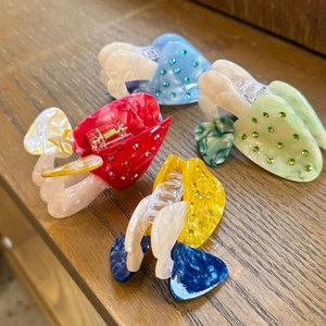 Macro shot of colorful acetate heart hair claws with rhinestones on a wooden table