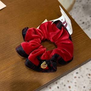 Détail d'un chouchou en velours rouge avec motif à carreaux et pendentif doré porte-bonheur