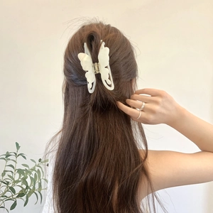 Macro detail of high-quality white butterfly hair claw clip with elegant acetate texture
