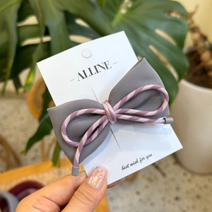Détail d'une pince à cheveux à nœud en tissu sergé gris sur une carte de présentation