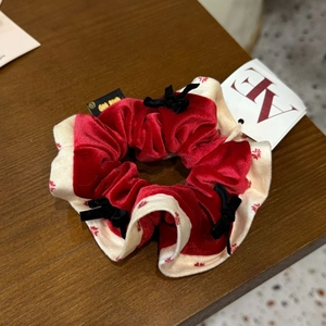 Détail d'un chouchou en velours rouge avec motifs de flocons et nœuds en soie noire