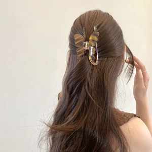 Detailed back view of a tortoiseshell butterfly claw clip holding a brunette bun hairstyle