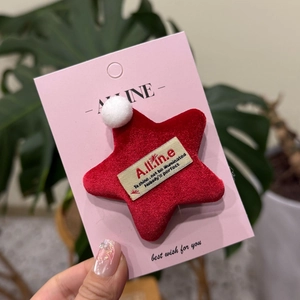 Vue détaillée de l'accessoire étoile en velours rouge avec pompon blanc sur carte
