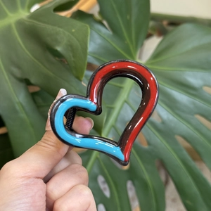 Close-up of heart-shaped hair claw clip with red, blue, and brown color block design