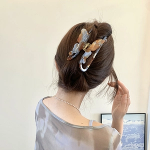 Elegant butterfly acetate hair claw clip with marble texture worn on a bun hairstyle