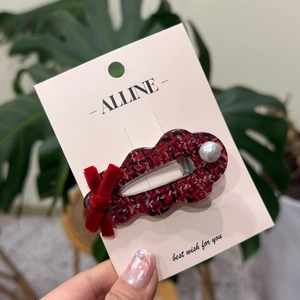 Détail de la pince à cheveux en tweed rouge avec nœud en velours et perle