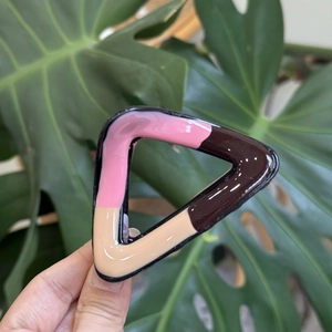 Detailed close-up of a three-color wave pattern geometric hair claw clip with glossy finish