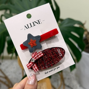 Détail d'une pince étoile rouge et d'une épingle en tweed chic sur carte blanche
